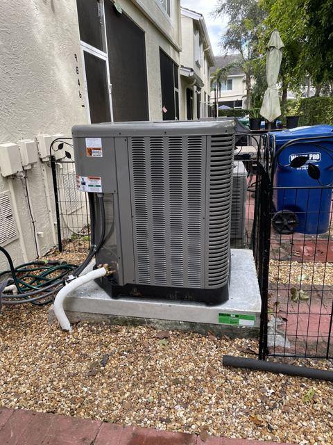 Townhome condenser replacement — Rheem condenser set on an elevated pad in a tight side yard (Wonder Air & Heat, Brevard County FL)